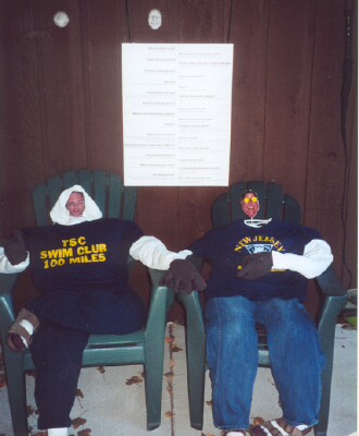 Two stuffed dummies sitting in chairs and holding hands, with a sign over their heads