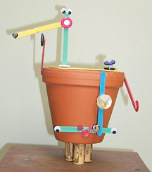 Photo: Clay garden pot decorated with Popsicle sticks and buttons to look vaguely human-like. Ignore the three corks standing in for feet.
