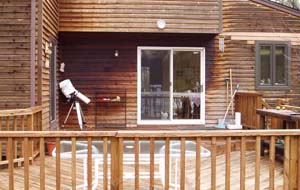 The deck at druid labs, with a telescope wrapped in plastic under the eave.